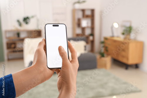 Obraz na płótnie Woman using blank mobile phone in living room, closeup w salonie