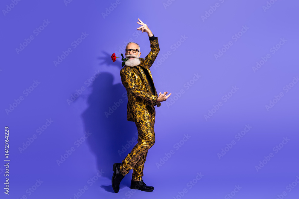 Stylish senior gentleman in a golden suit performs a playful dance holding a rose against a vibrant violet background Stylish senior gentleman in a golden suit performs a playful dance holding a rose against a vibrant violet background