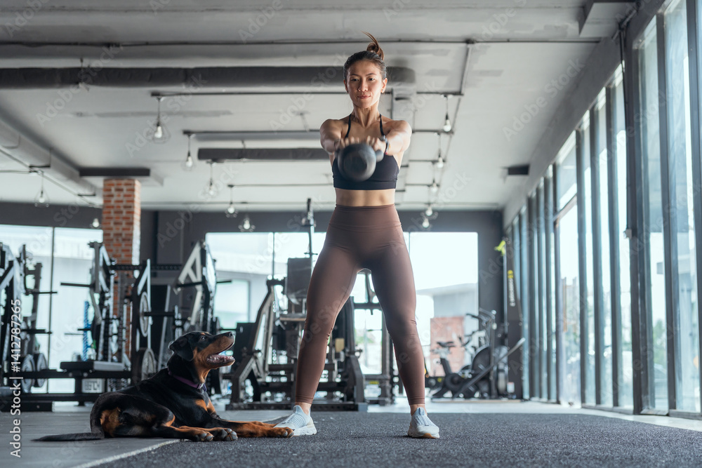Fototapeta premium Woman exercises with weights in gym while dog relaxes nearby during morning workout session