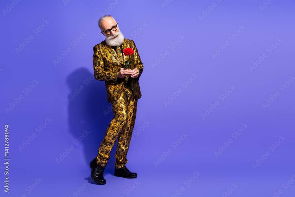 Elegant mature man in an extravagant gold patterned suit holding a red rose with a confident pose against a vibrant violet background Elegant mature man in an extravagant gold patterned suit holding a red rose with a confident pose against a vibrant violet background