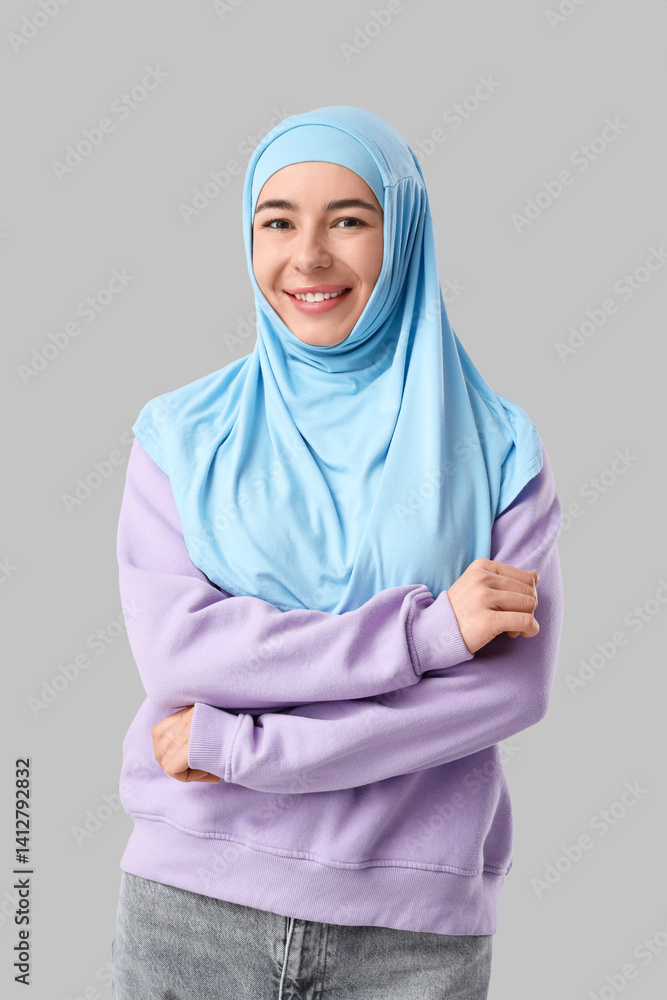 Happy young Muslim woman in hijab on grey background Happy young Muslim woman in hijab on grey background