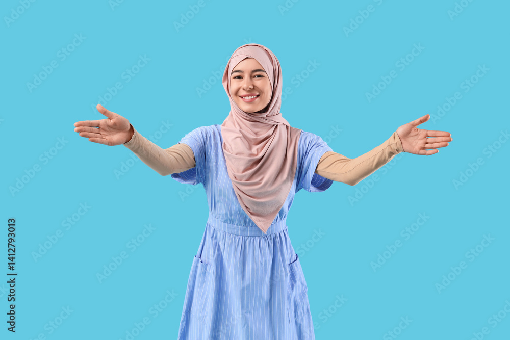 Happy young Muslim woman in hijab on blue background Happy young Muslim woman in hijab on blue background