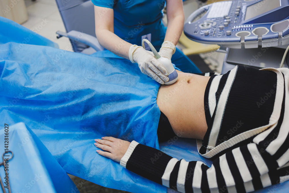 Ultrasound examination of the abdomen of a pregnant woman. Close-up of the abdomen of a pregnant woman. Checking the condition of the fetus using a sensor through the abdomen.