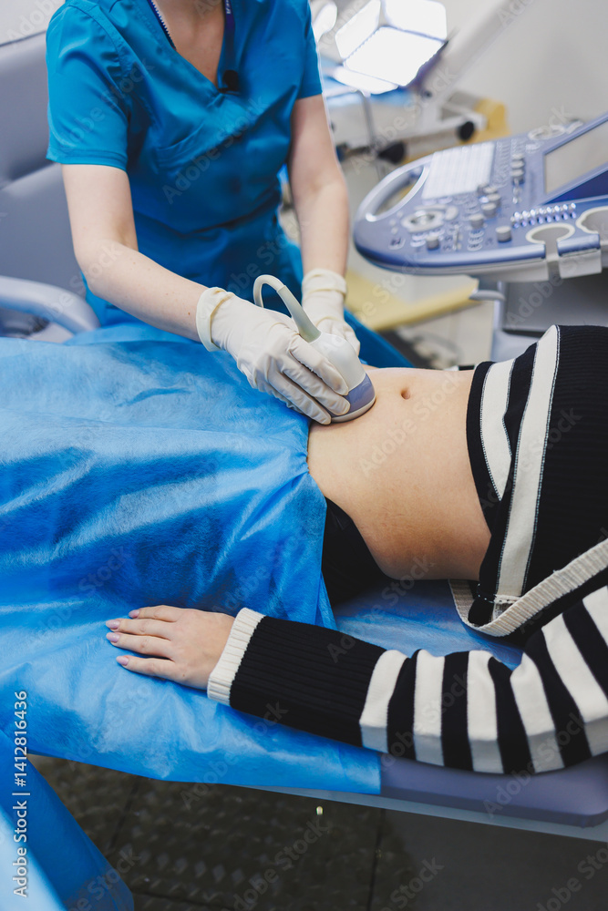 Ultrasound examination of the abdomen of a pregnant woman. Close-up of the abdomen of a pregnant woman. Checking the condition of the fetus using a sensor through the abdomen.