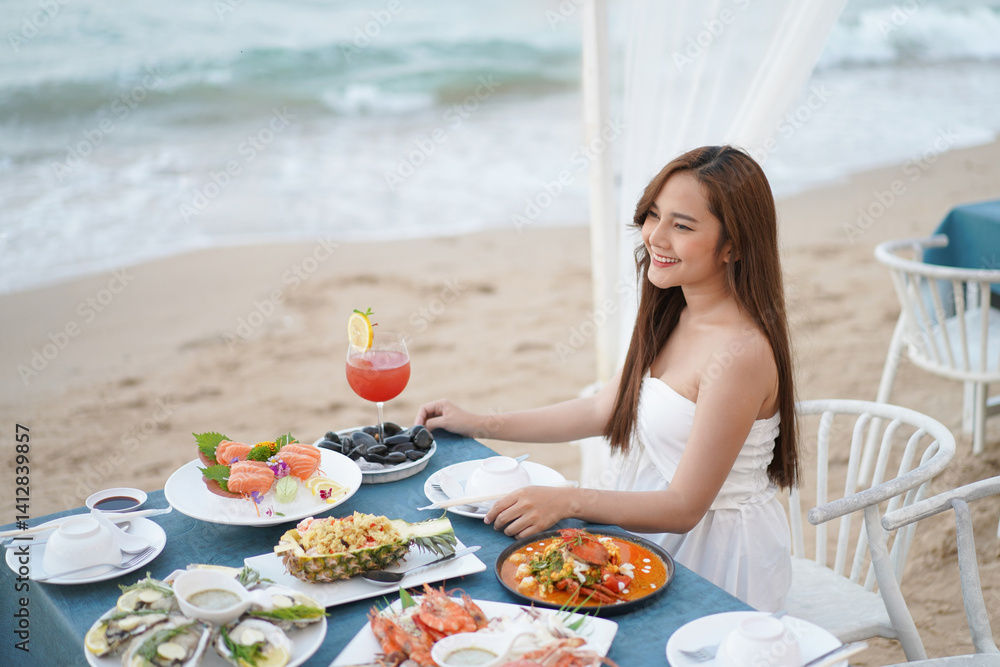 woman in white dress enjoys beachside meal with seafood and cocktail, smiling and relaxed by ocean