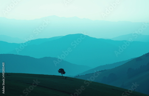 Misty mountains in teal tones, lone tree on grassy hill.