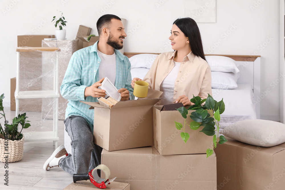 Happy young couple packing belongings in bedroom on moving day Happy young couple packing belongings in bedroom on moving day