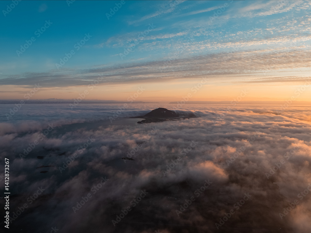 View from above, stunning aerial view of Hverfjall volcano at sunset surrounded by beautiful fluffy clouds. Hverfjall is a fascinating volcano in Northern Iceland, near Lake Mývatn
