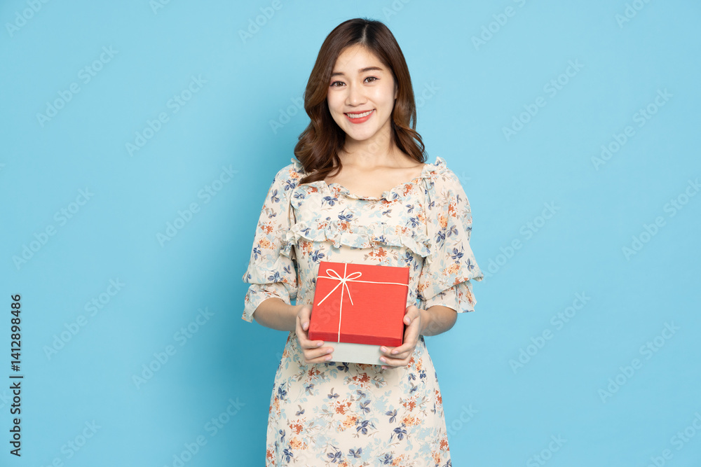 Happy Asian woman holding red gift box isolated on light blue background, New year or Happy birthday concept Happy Asian woman holding red gift box isolated on light blue background, New year or Happy birthday concept
