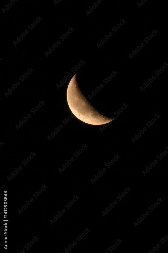 Close-up shot of a waxing crescent moon against a pitch-black night sky. Detailed craters and surface textures are visible in this minimal and captivating lunar image.