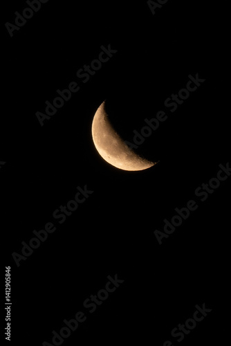 Obraz na płótnie Close-up shot of a waxing crescent moon against a pitch-black night sky. Detailed craters and surface textures are visible in this minimal and captivating lunar image. w salonie