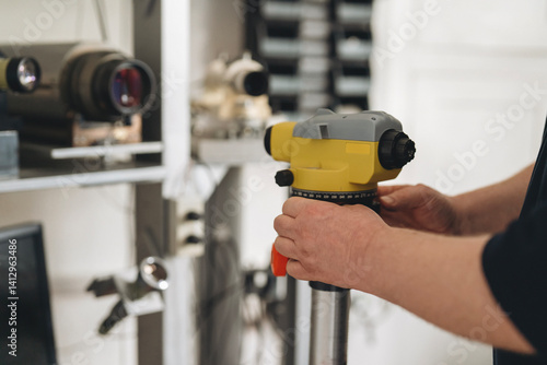 Foto Technician in jobbing shop mounting autolevel on stand for repair and precision