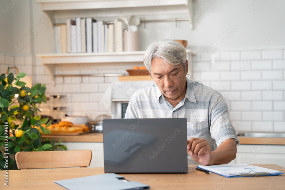 Asian senior man learning or working with laptop in the morning at home, managing finance document, home payment after retirement Asian senior man learning or working with laptop in the morning at home, managing finance document, home payment after retirement