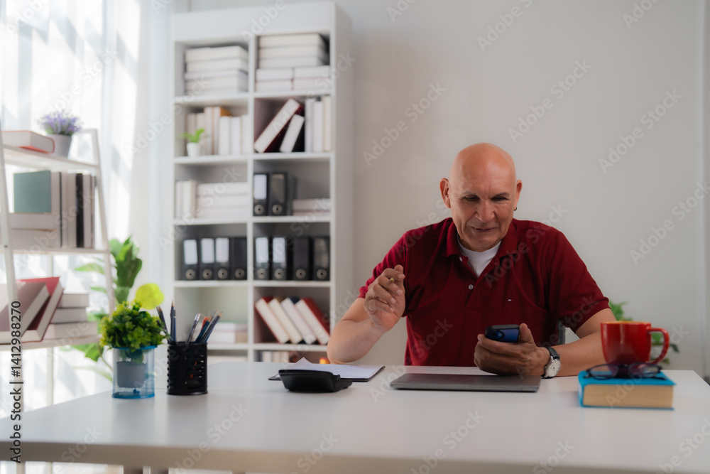 Confident mature businessman sitting at desk and using smartphone while working in modern office, surrounded by books, files, and office supplies Confident mature businessman sitting at desk and using smartphone while working in modern office, surrounded by books, files, and office supplies