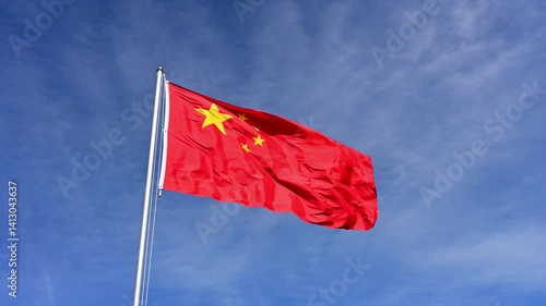 Chinese flag waving in front of a summery blue sky, slow motion