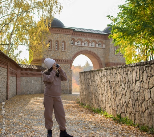 A ten-year-old girl photographs an arch and a fortress with brick and stone on an autumn day