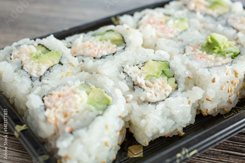 Slika na platnu A closeup view of a tray of California roll sushi.