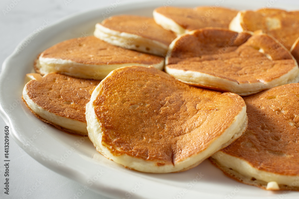 A closeup view of a plate of small pancakes. A closeup view of a plate of small pancakes.