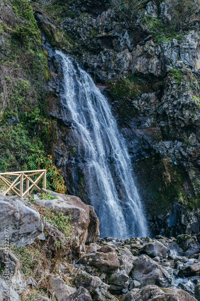 A beautiful waterfall gracefully cascades down verdant cliffs in Sao Jorge, Azores, Portugal. A serene and picturesque scene of natural beauty