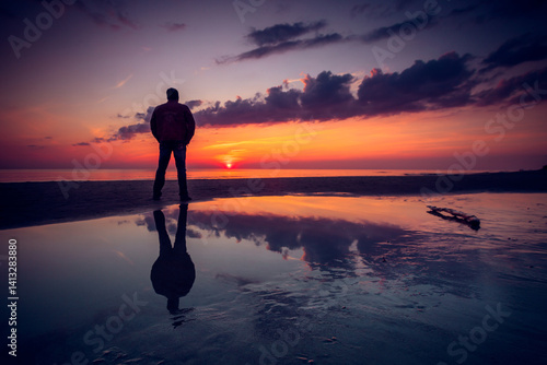 Rear view silhouette of a man standing on a beach by the Baltic Sea at sunset, Lithuania
