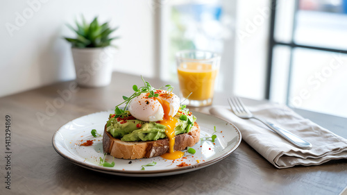 Open-faced sandwich with poached egg, avocado, and sauce, with orange juice