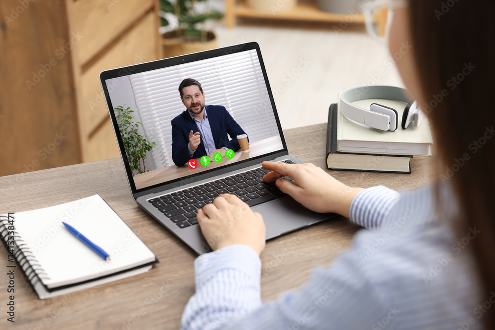 Fototapeta premium Woman listening to speaker via laptop online at table, closeup