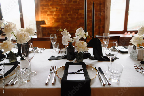 A beautifully arranged dinner table showcasing black candles and white roses, perfect for a special occasion or celebration.