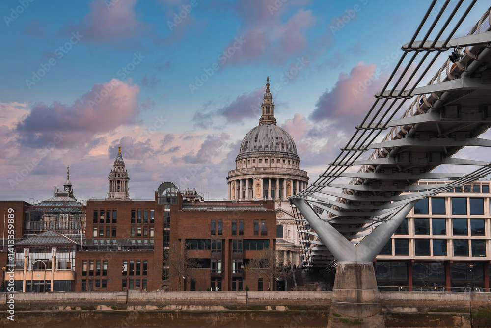 St. Paul's Cathedral's dome stands out against a colorful sky, with the Millennium Bridge to the right and urban buildings along the Thames River in view.