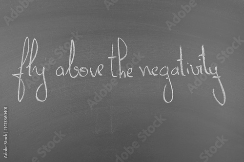 Motivational quote on chalkboard: Fly above negativity. Encouragement to overcome challenges and maintain a positive outlook.