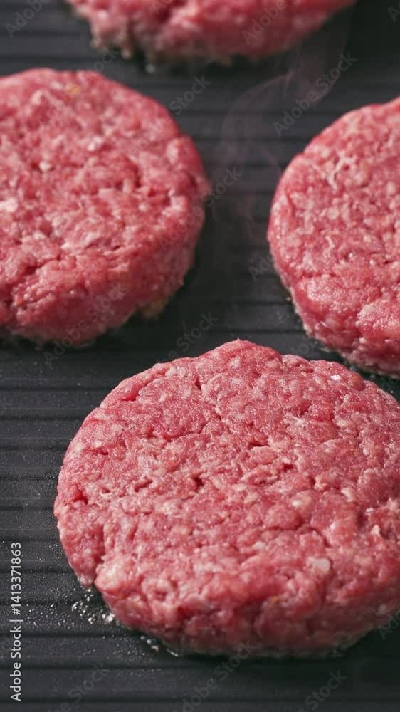 chef puts fresh raw red ground beef burger meat patties on hot electric grill to cook, food closeup chef puts fresh raw red ground beef burger meat patties on hot electric grill to cook, food closeup