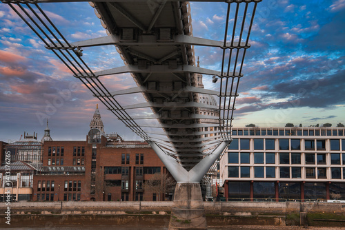 Obraz na płótnie View of the Millennium Bridge's suspension cables and modern design, with St. Paul's Cathedral dome in the background under a colorful sky. w salonie