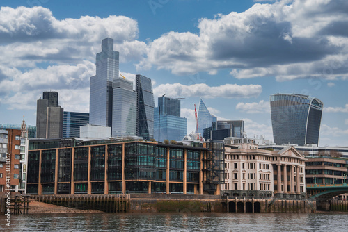 Obraz na płótnie The London skyline features the Walkie Talkie and Leadenhall buildings, with historic riverside architecture and the Thames River under a partly cloudy sky. w salonie