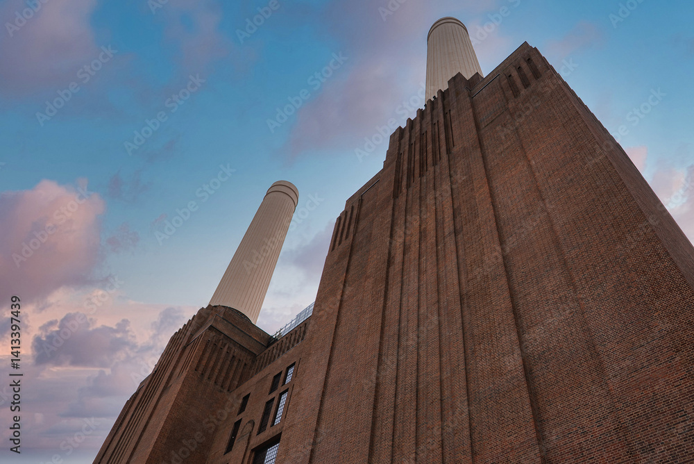 The iconic Battersea Power Station in London features Art Deco architecture, four white chimneys, and a vibrant sky with pink and blue hues.