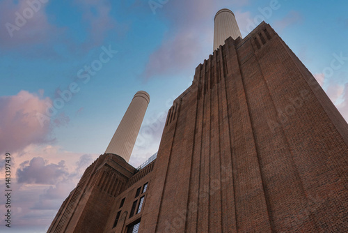Obraz na płótnie The iconic Battersea Power Station in London features Art Deco architecture, four white chimneys, and a vibrant sky with pink and blue hues. w salonie