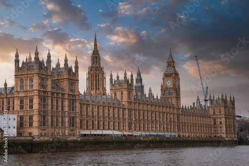 Obraz na płótnie The Palace of Westminster and Big Ben in London, England, with Gothic Revival architecture, a dramatic sky, and the River Thames in the foreground. w salonie