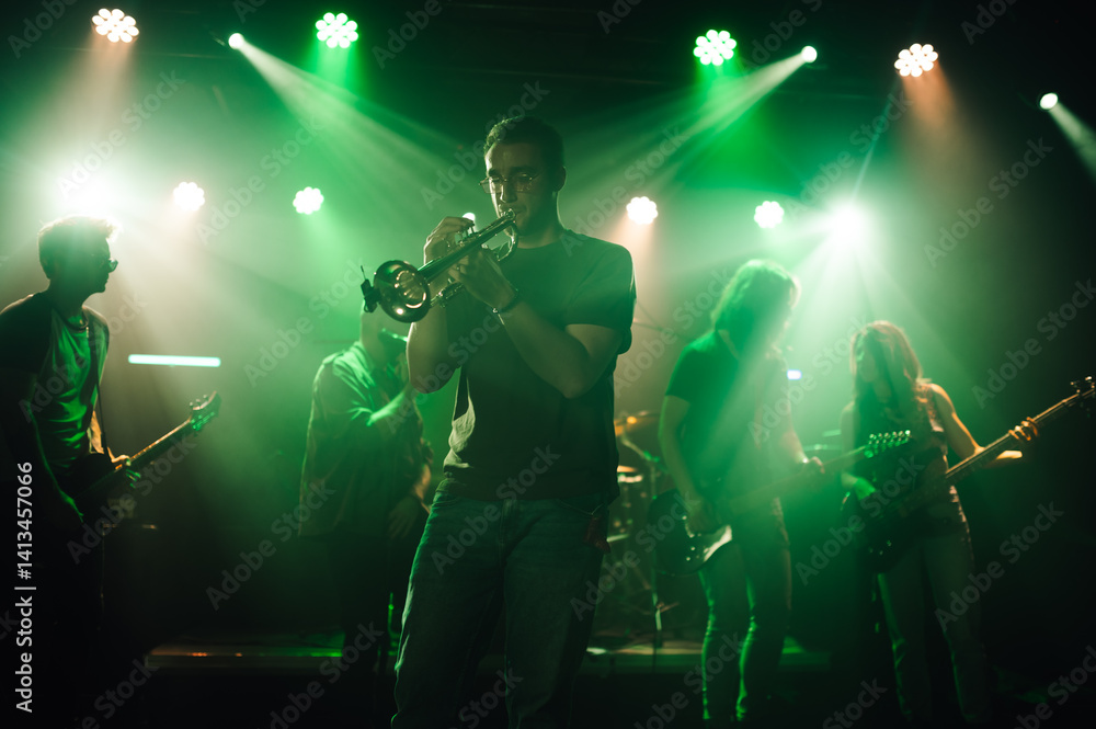 Fototapeta premium Trumpet player performing with band on stage under green lights