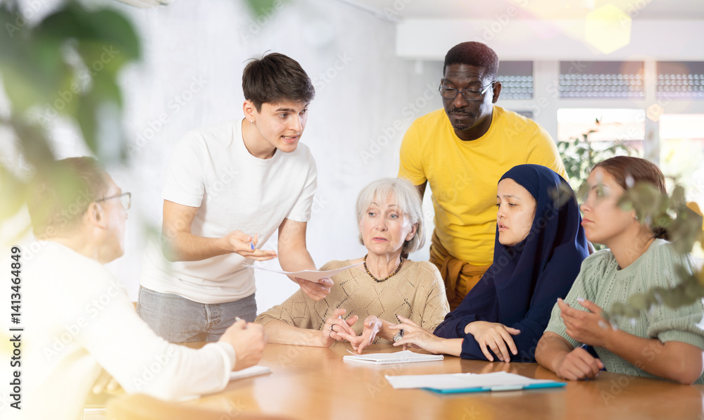 Group of multinational people making notes in documents at table in office Group of multinational people making notes in documents at table in office