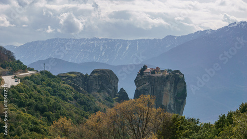 Fototapeta Naklejka Na Ścianę i Meble -  Landscape of Meteora with Holy Trinity Monastery on top of the rocks and snow capped mountains in background, Kalambaka, Thessaly, Greece