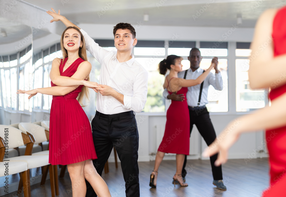 Naklejka premium Energy man and young woman are dancing classic version of waltz in couple during lesson at studio. Leisure activities and physical activity for positive people.