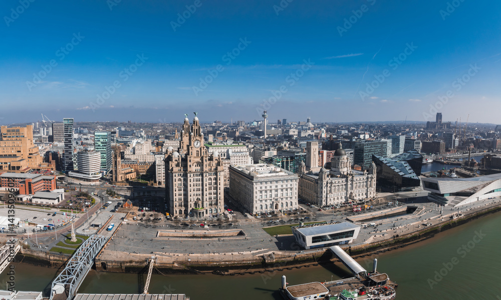 Aerial view of Liverpool, England, featuring the Royal Liver Building, Cunard Building, Port of Liverpool Building, and the Mersey River in the foreground.