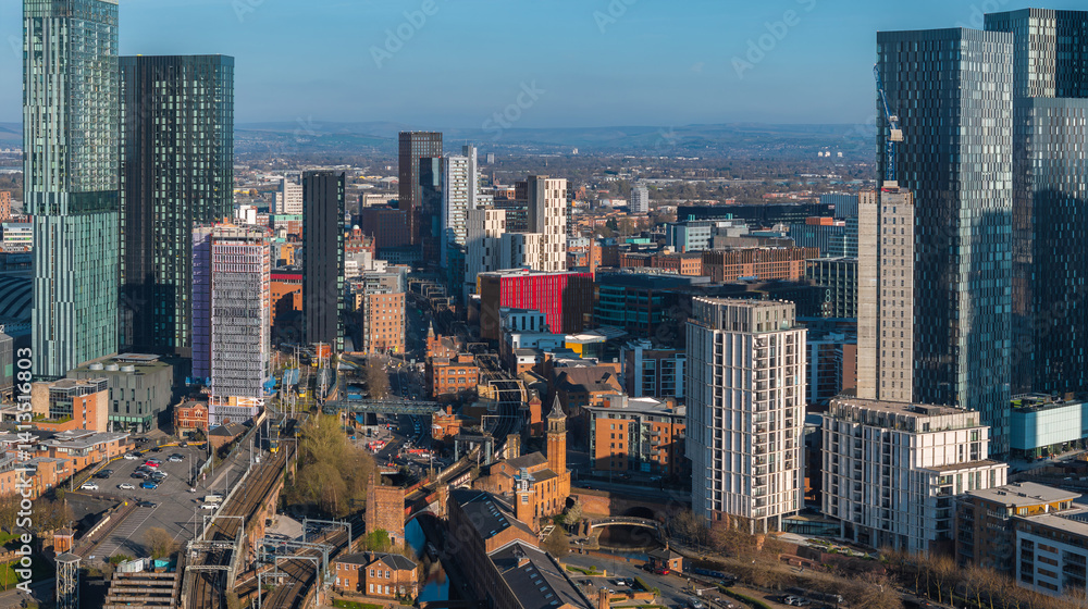 Aerial view of Manchester, UK, showcasing skyscrapers like Beetham Tower, railway tracks, canals, and a mix of modern and historic architecture.