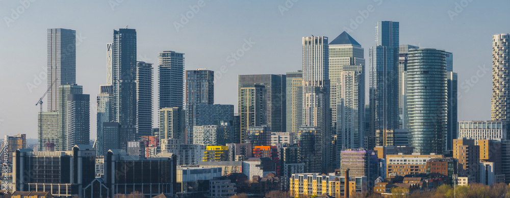 Panoramic view of Canary Wharf in London, showcasing One Canada Square and other skyscrapers surrounded by residential and commercial buildings.