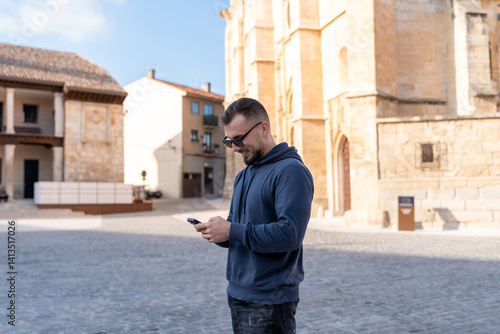 Tourist using smartphone in front of collegiate church of santa maria la mayor, toro, spain photo