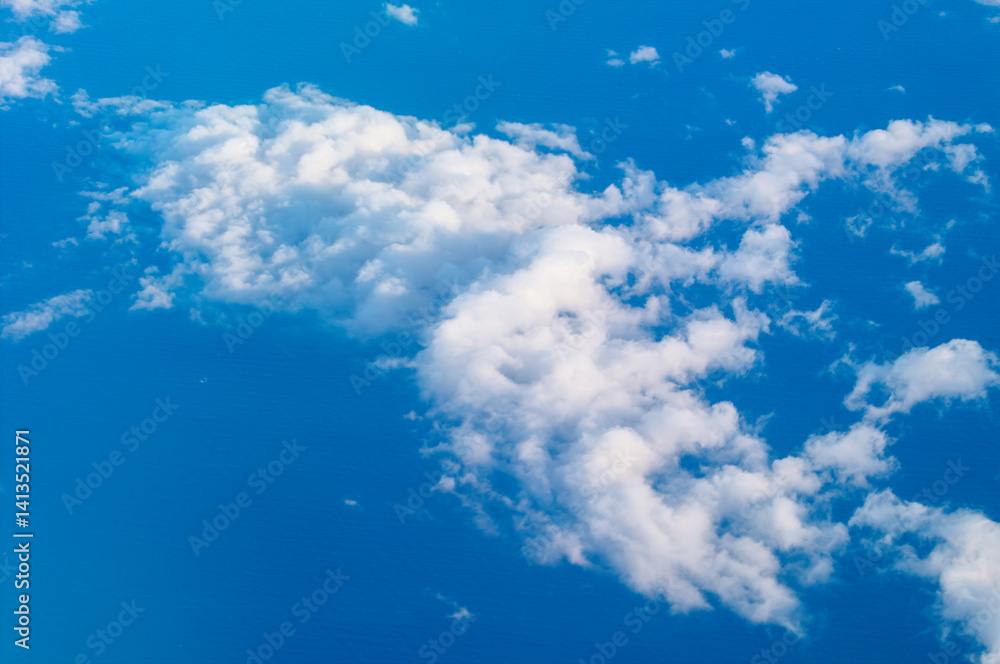 Vibrant blue sky stretched endlessly, filled with clusters of fluffy white clouds. Serene aerial view captures the beauty of the heavens in a calming, ethereal scene