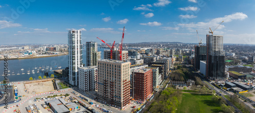 Obraz na płótnie Aerial view of London's urban area with high rise buildings, construction cranes, the River Thames on the left, and a green park in the foreground. w salonie