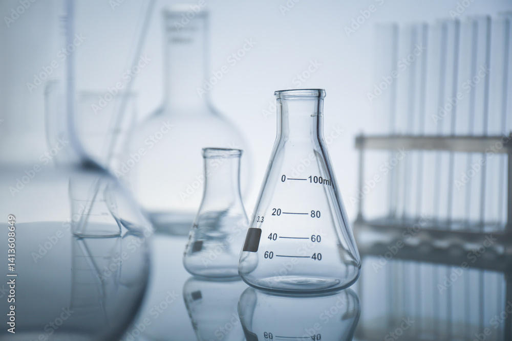 Laboratory glassware on mirror surface against light background Laboratory glassware on mirror surface against light background