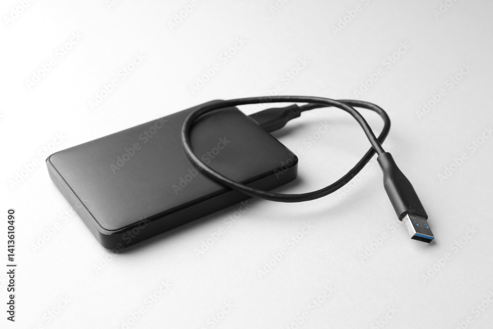 External hard drive with USB cable on white background, closeup External hard drive with USB cable on white background, closeup