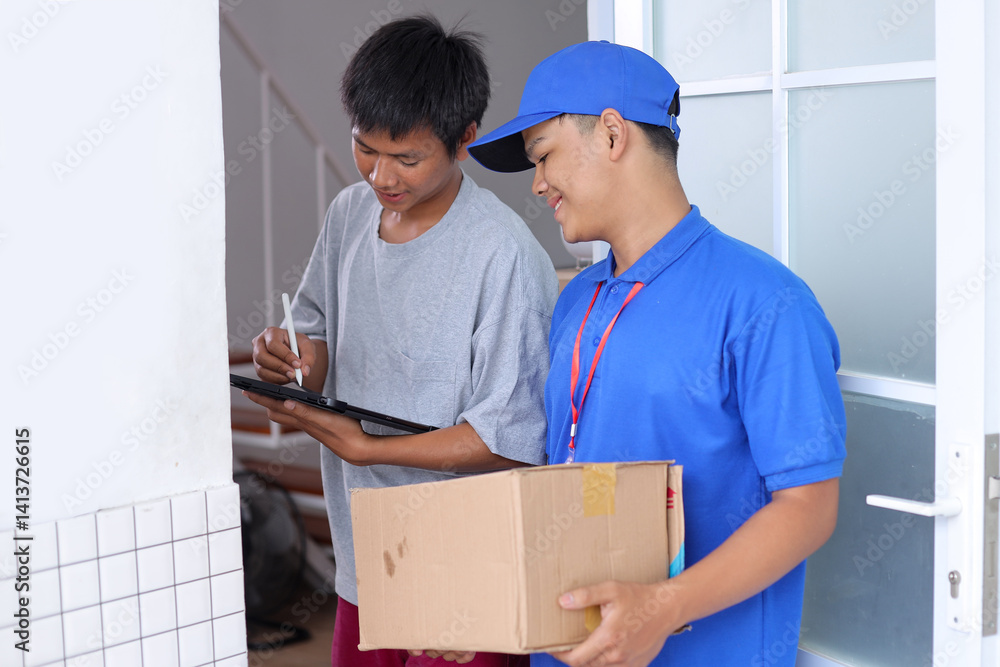 Young Man Sign In Digital Tablet After Receiving Parcel From Courier At Home. Young Man Sign In Digital Tablet After Receiving Parcel From Courier At Home.