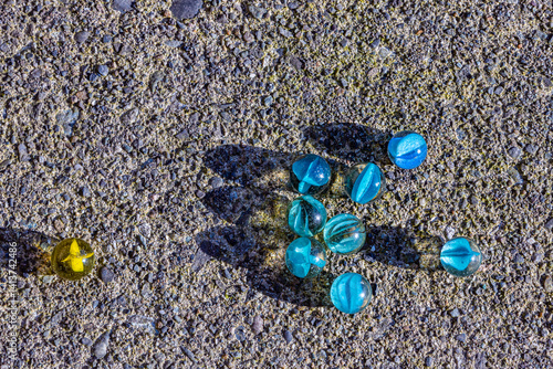A few marbles are scattered on the ground, with one of them being yellow. a group of blues leaving out yellow