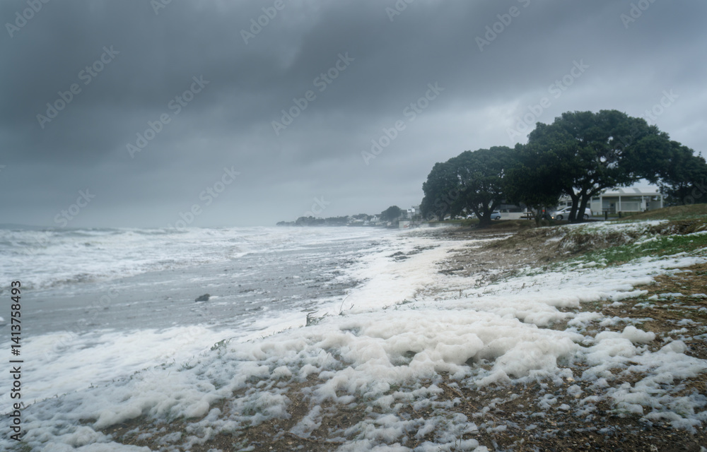 Strong winds send sea foam flying to the beach. Milford Beach. Auckland.